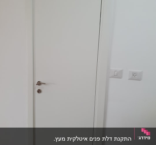 דלת לבנה עם ידית מתכת על קיר לבן